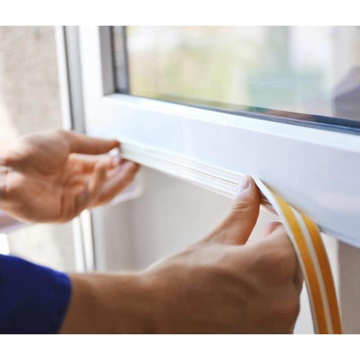 a person placing weather stripping on a white window